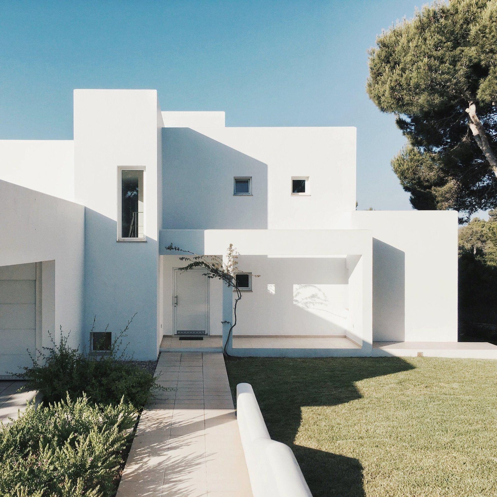 A white building facade with rectangular windows and a recessed entrance.
