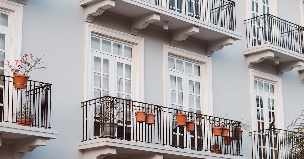 Apartment balconies with black railings, white doors and potted plants.