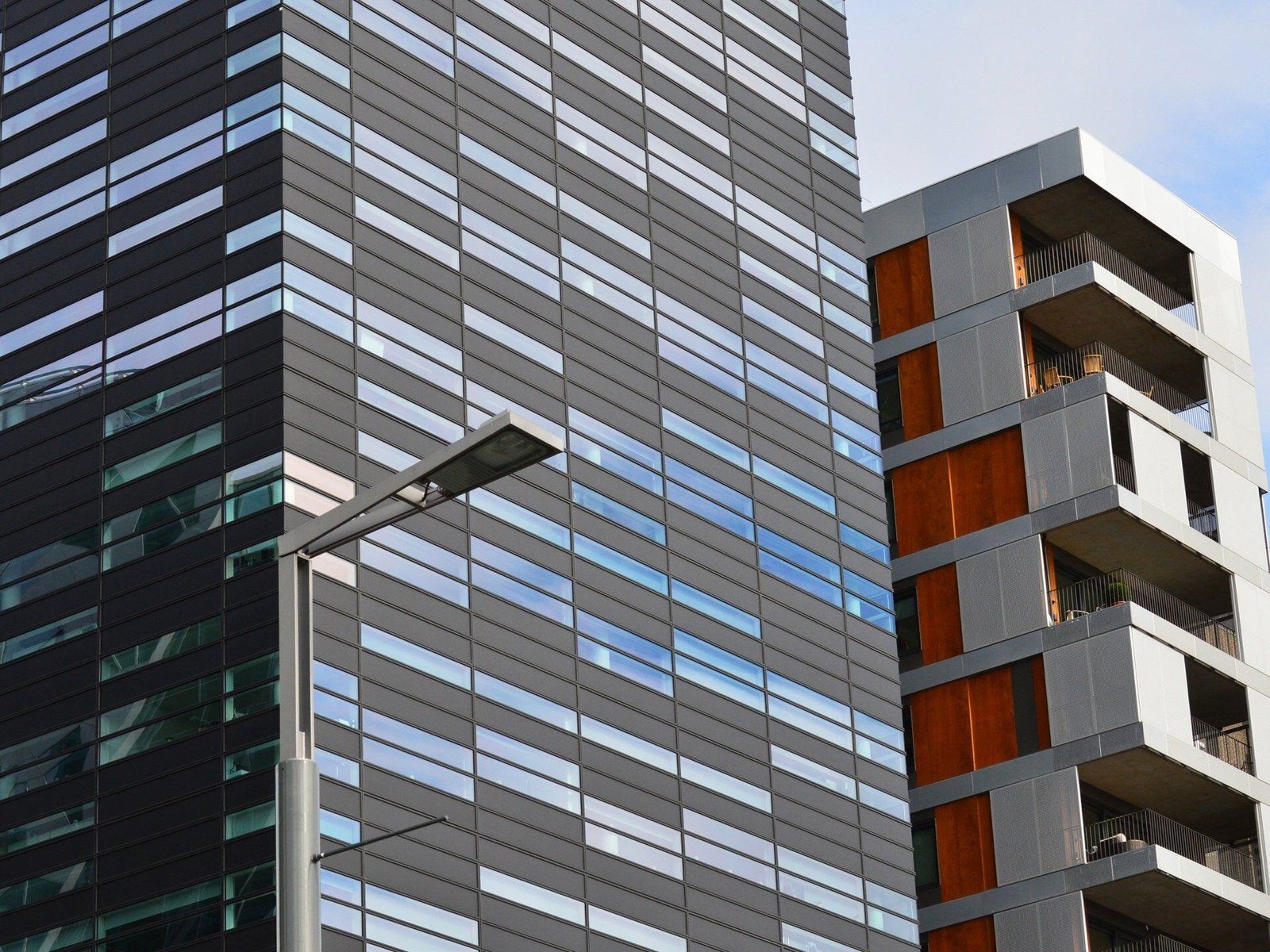 The exterior of a modern building with glass windows, balconies and gray facade panels.