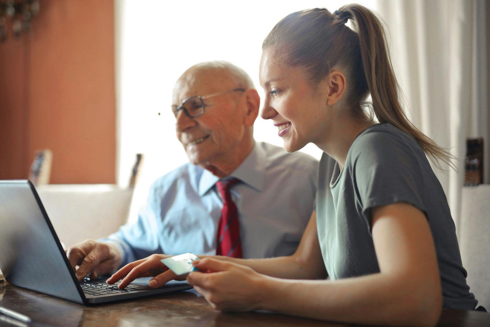 Two people sitting together at a table and looking at a laptop.