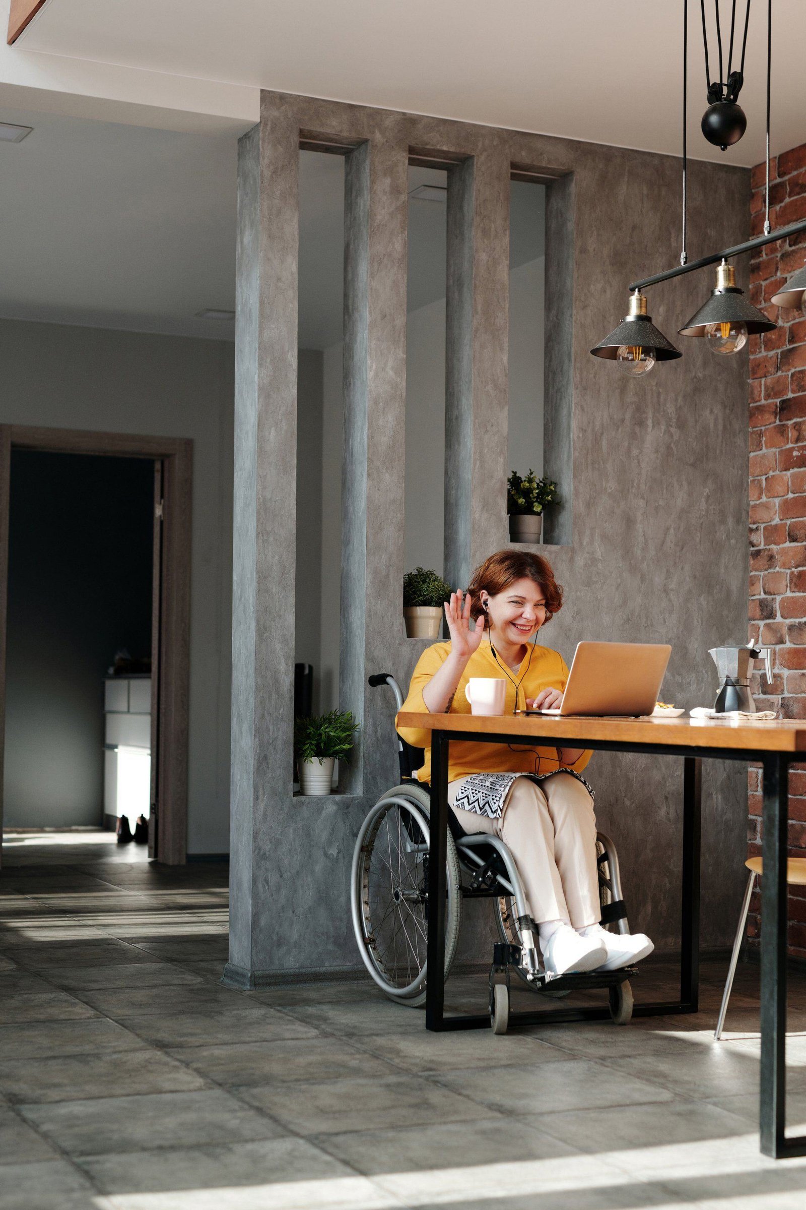 Woman seated in a wheelchair using a laptop at a table.