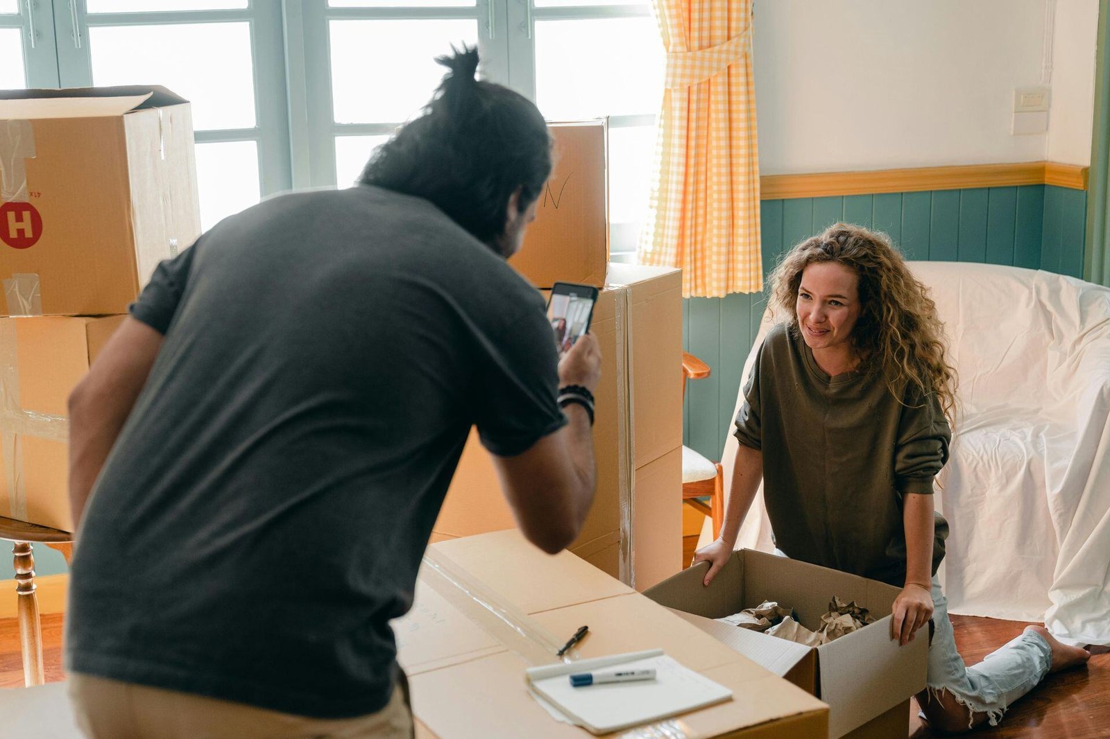 Two people among cardboard moving boxes, one holding a phone.