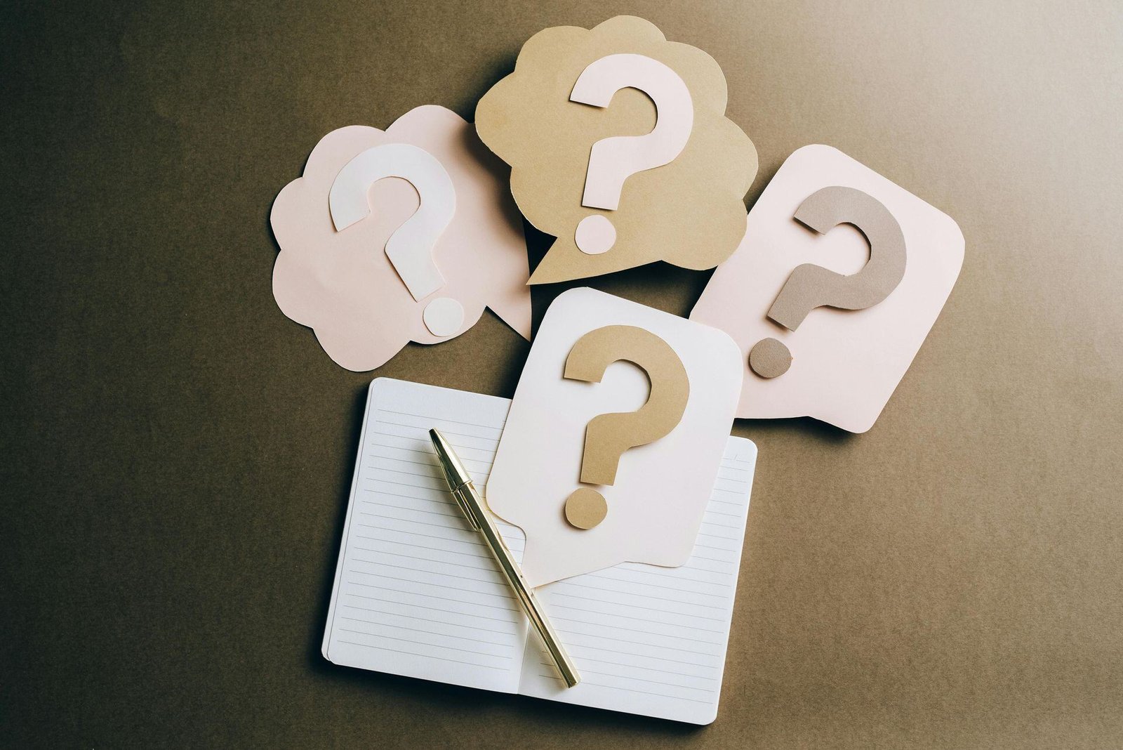 Question-mark cards beside an open notebook and pen.