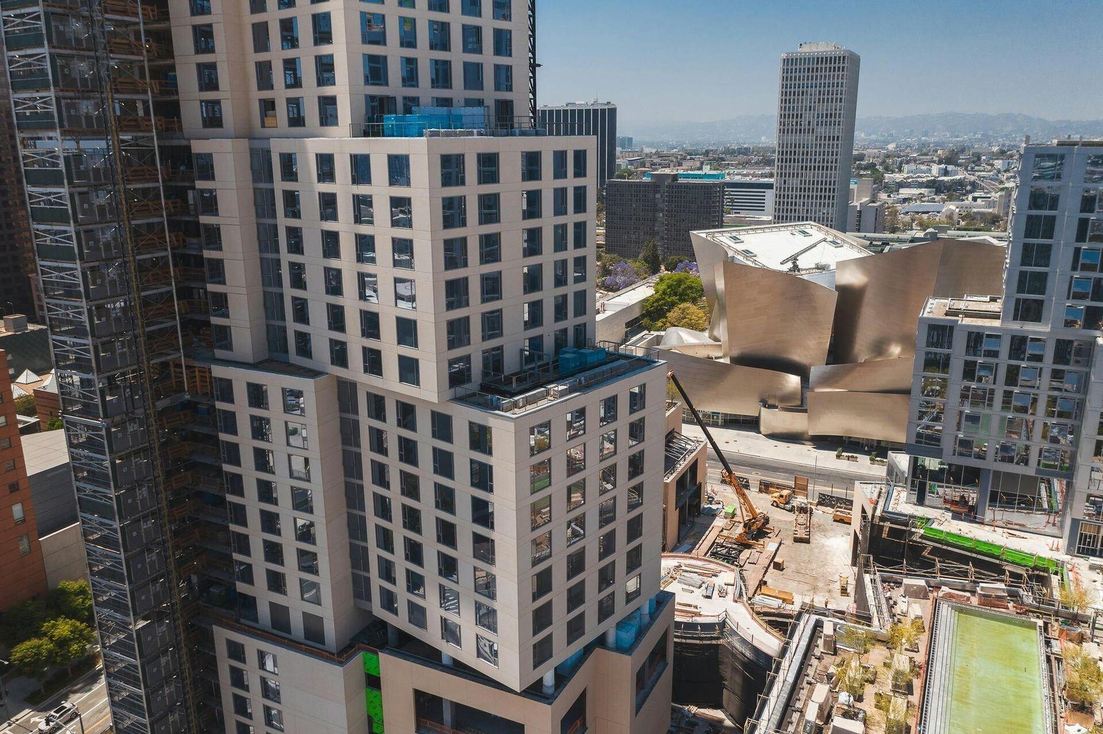 High-rise buildings and a construction site beside a curved metal-clad building.