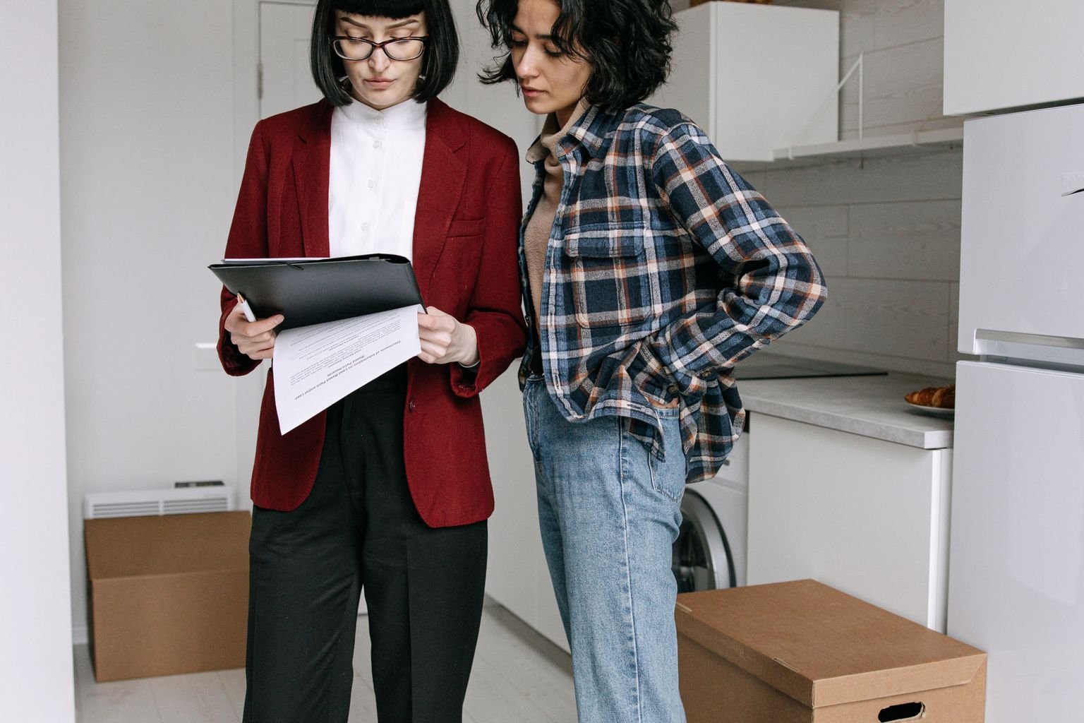 A property manager and resident reviewing documents together inside an apartment.