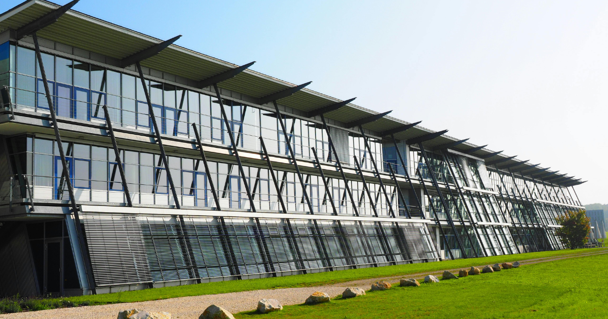 A modern office building with solar panels installed on the roof under a clear sky.