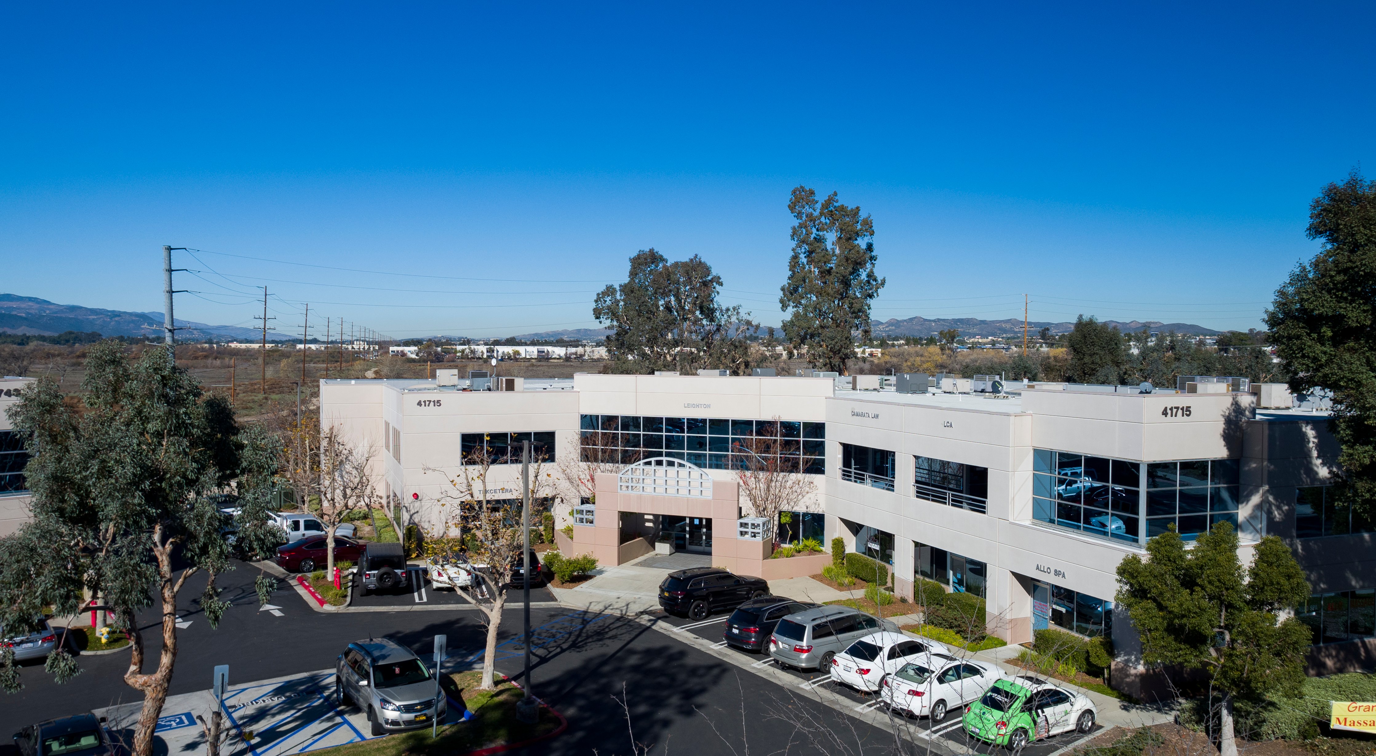 Modern commercial office building with parking and mature landscaping.