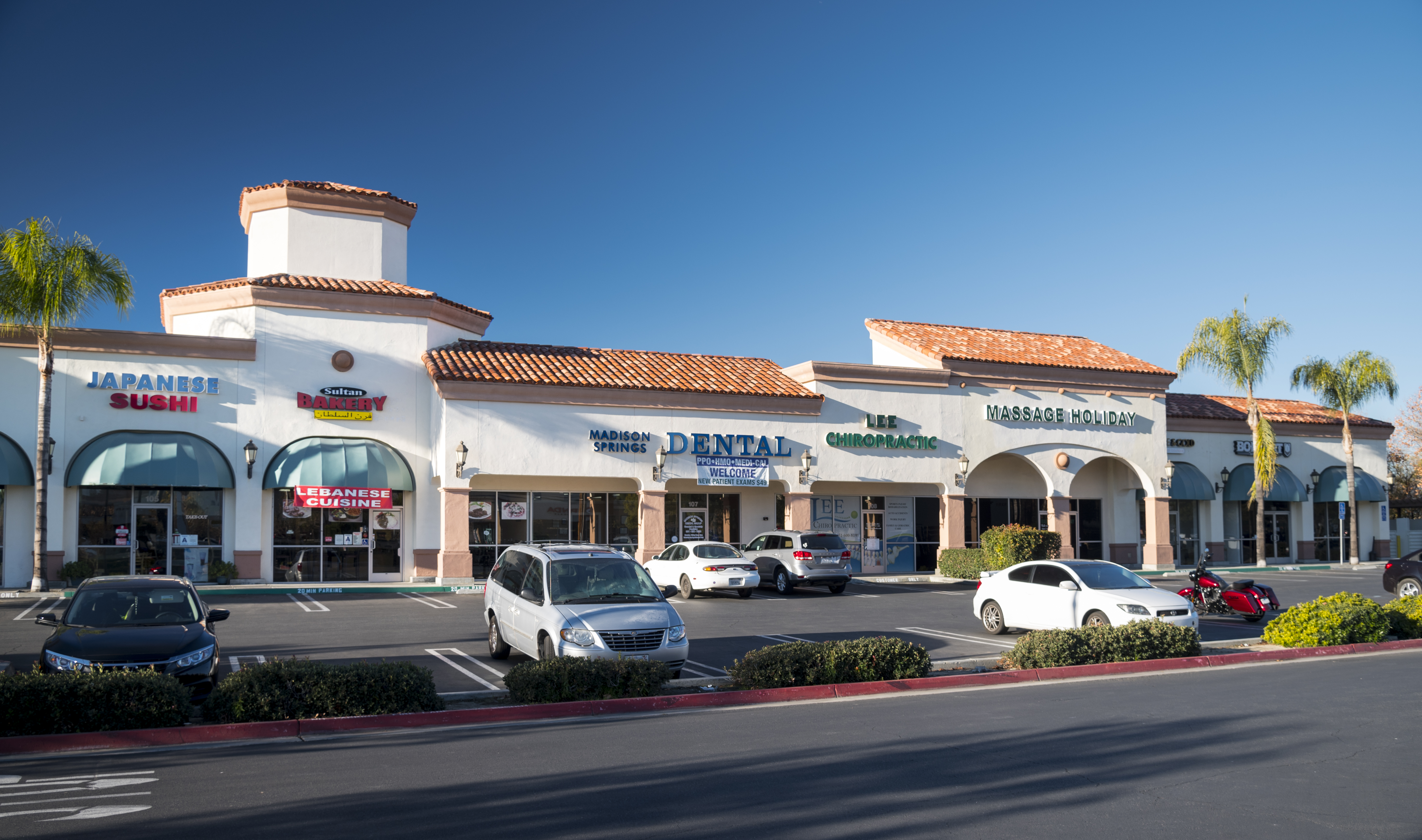 Retail center storefronts and parking area in Southern California.