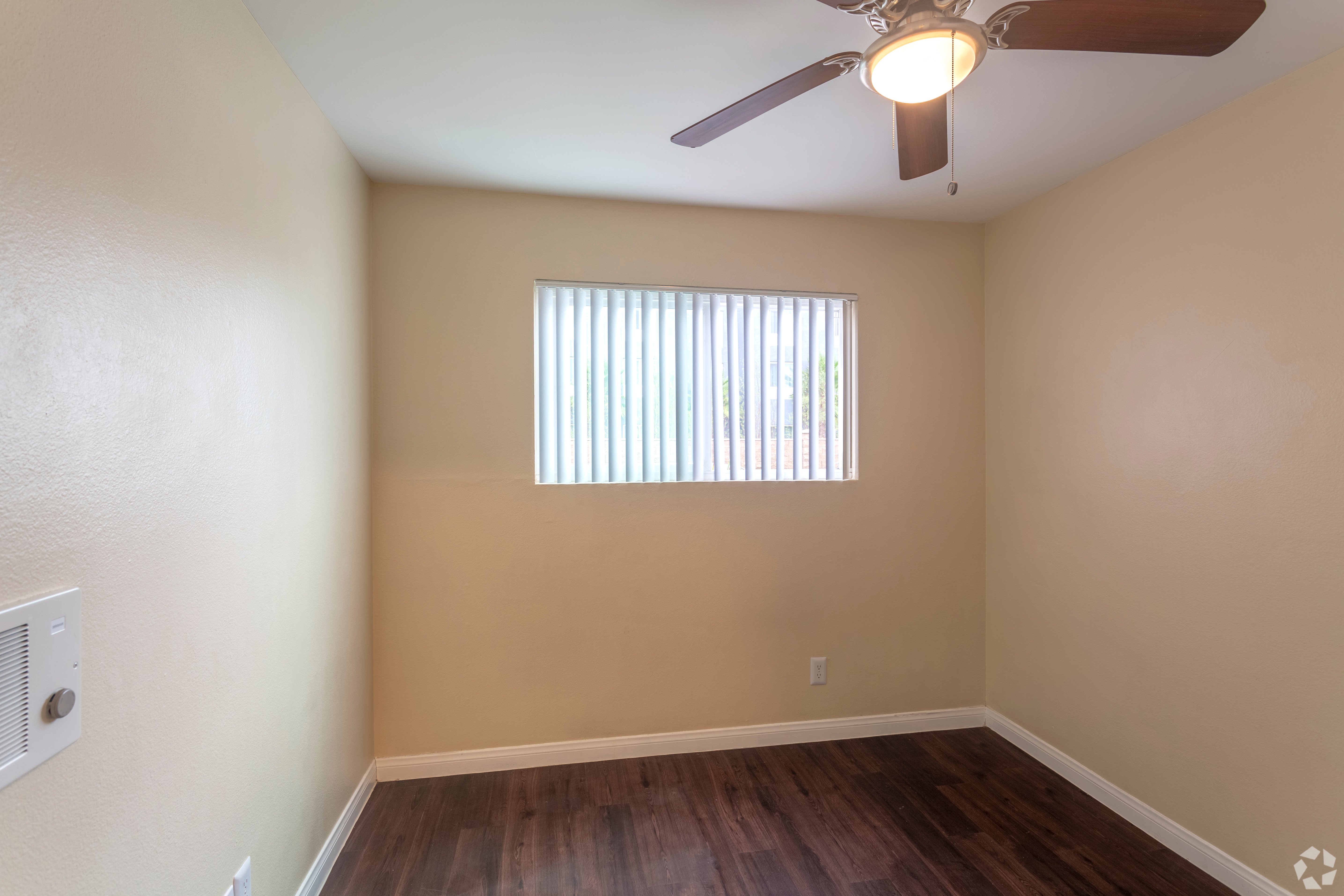 Empty apartment bedroom with finished flooring, a ceiling fan, and a window.
