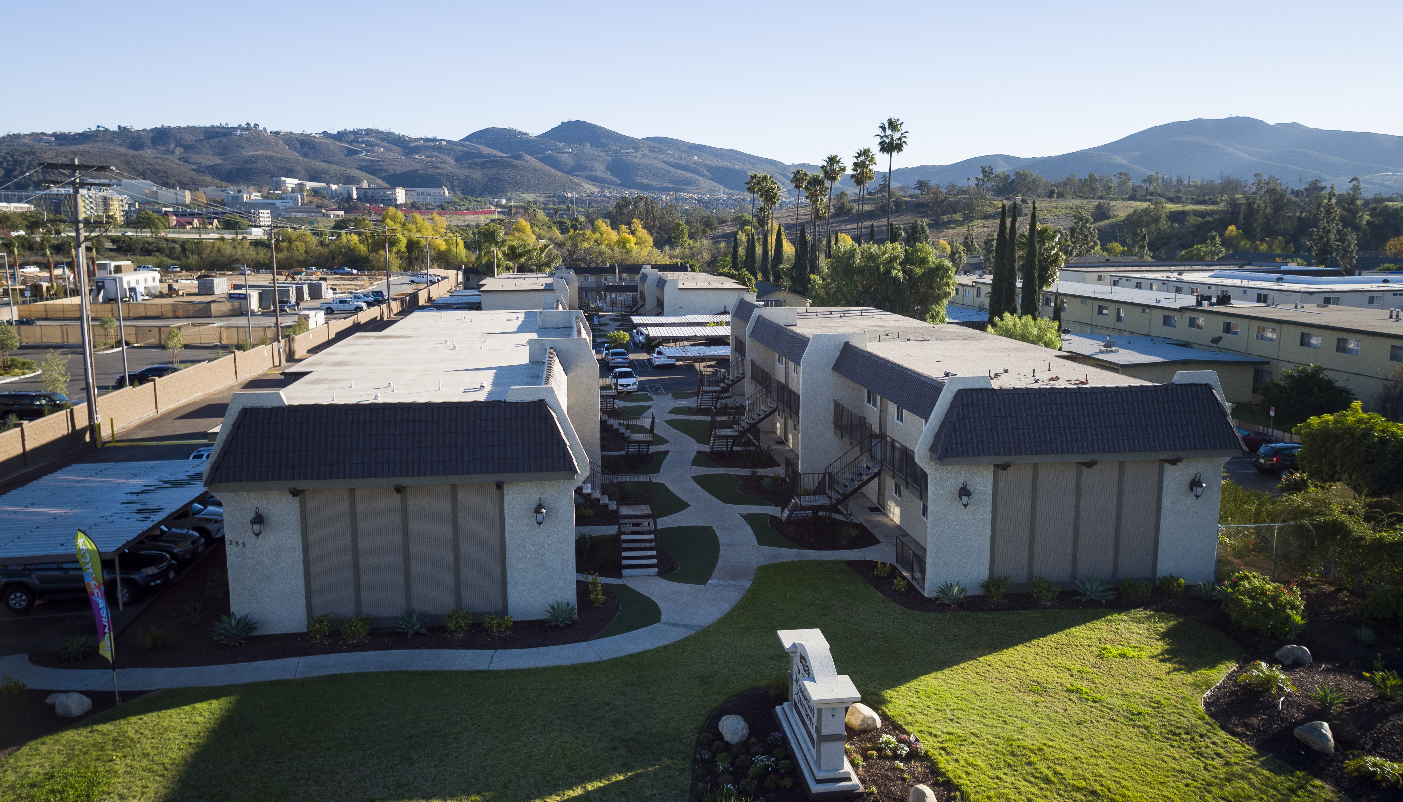 Aerial view of a multifamily apartment community with multiple buildings, landscaped courtyards, and mountain views.