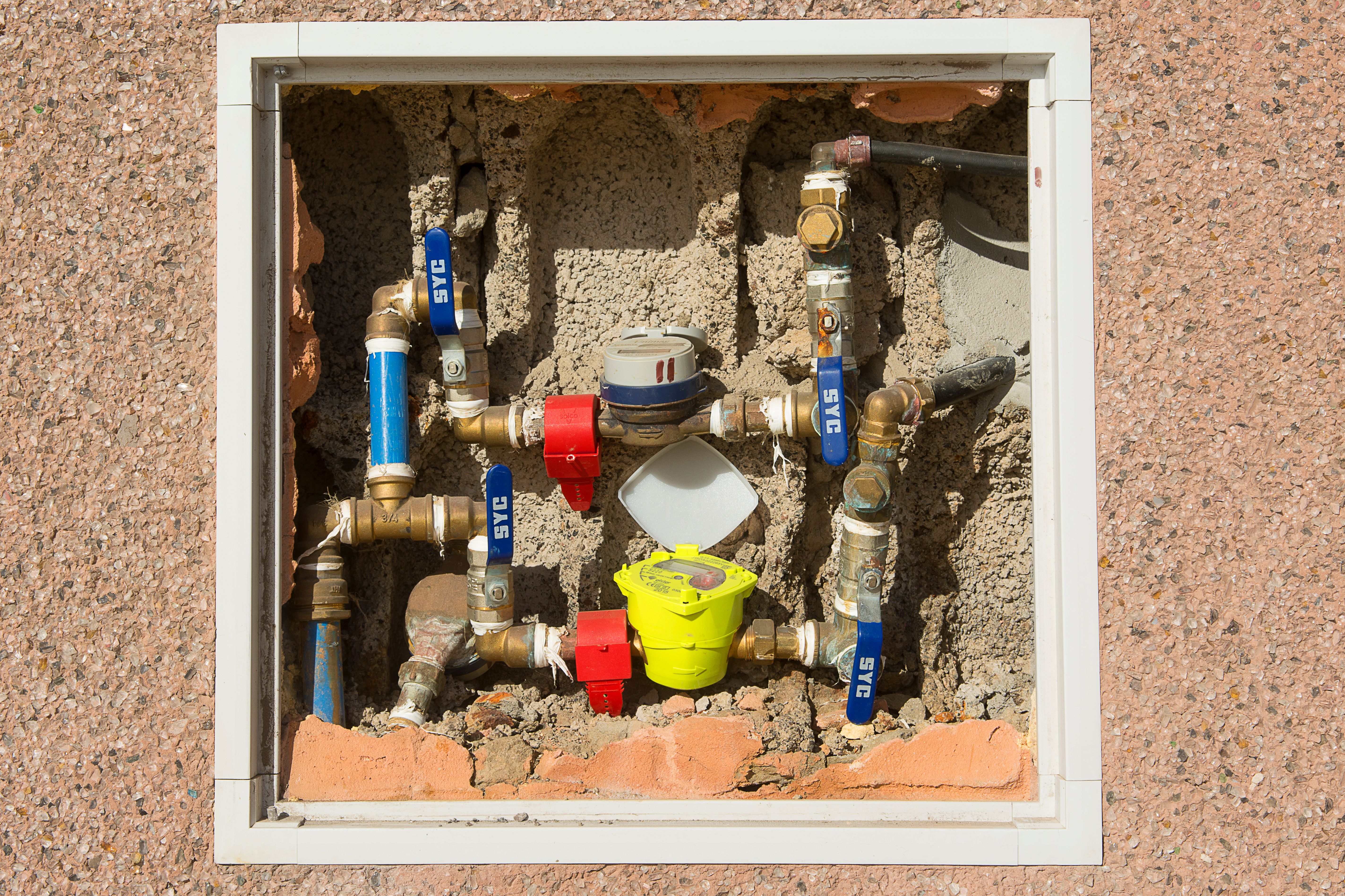 Close view of a water meter assembly with pipes and shutoff valves.