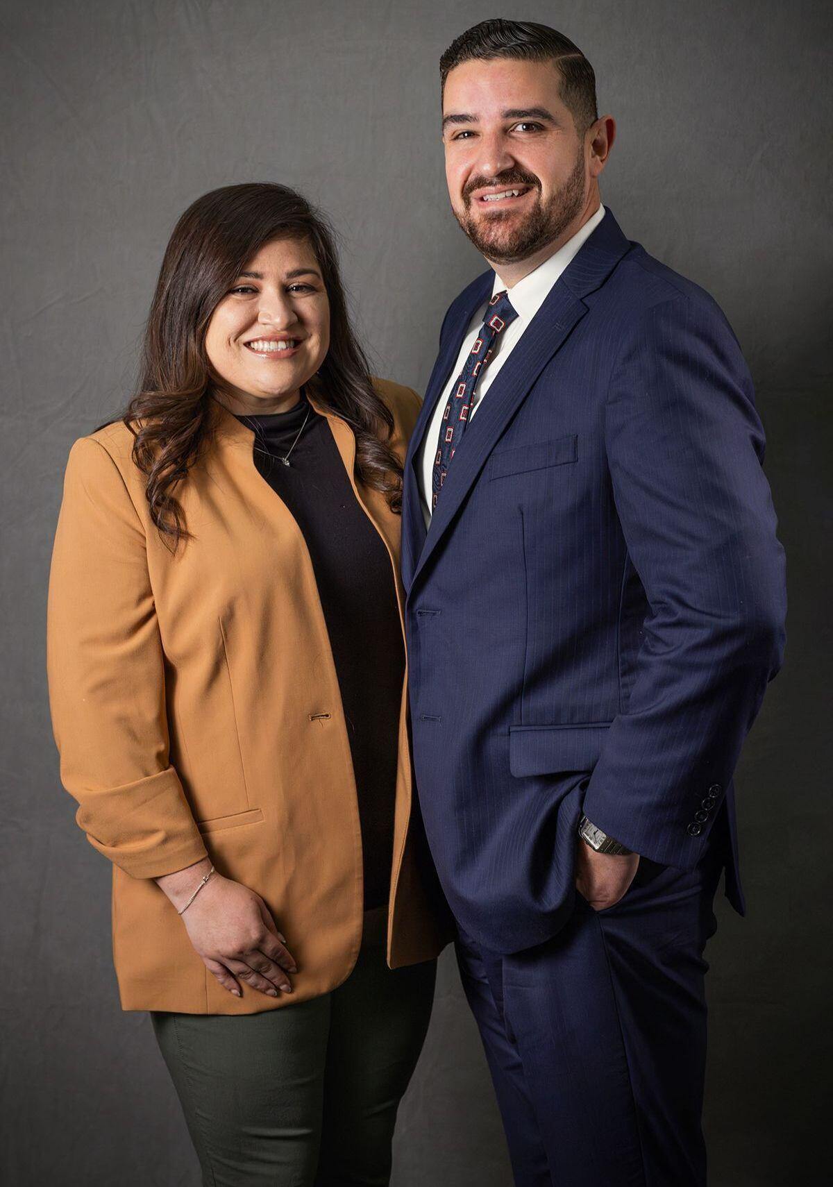 Two people posing for a portrait, one wearing a dark suit.
